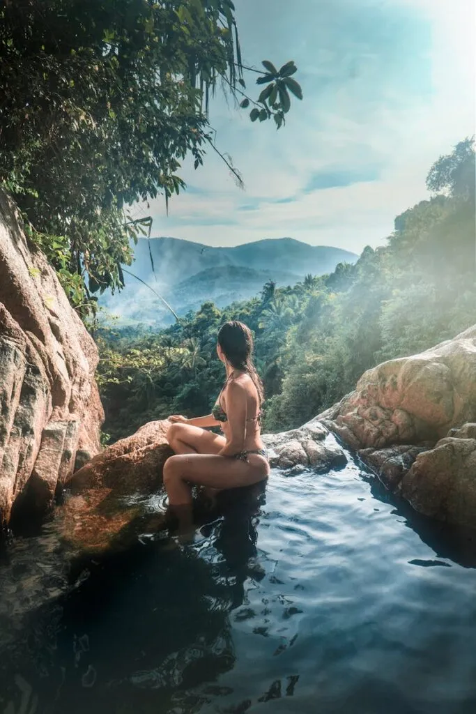 Woman Wearing Bikini Sitting on Rock Formation Near Trees