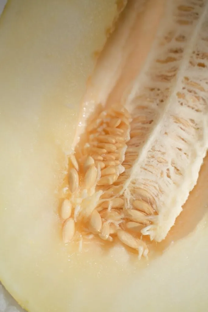 Detailed extreme close-up of a halved yellow melon showing seeds and texture.